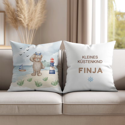 Handgezeichnetes Kinderkissen mit Matrosen-Bär, Leuchtturm und Segelschiff im Aquarell-Stil – Motiv Kleines Küstenkind.